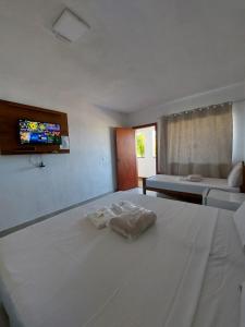 a bedroom with two beds and a tv on the wall at Pousada Escarpas in Capitólio