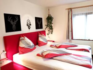 1 Schlafzimmer mit 2 Betten mit roten Kopfteilen in der Unterkunft Apartments Fasl in Gosau