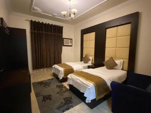 una camera d'albergo con due letti e una sedia di منازل الرؤية الفندقية a Najran