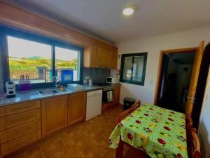 Una cocina con una mesa y un fregadero y una ventana. en Casa Brisa do Mar, en Ponta Delgada