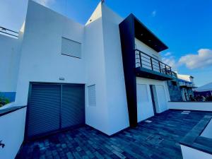 Casa blanca con puerta y balcón en Casa Brisa do Mar, en Ponta Delgada
