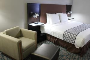 una habitación de hotel con una cama y una silla en Westbridge Inn & Suites, en Carrollton 17 fotos más