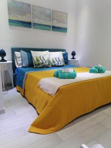 a large bed with a yellow and blue blanket on it at La Casetta del Ronco1 Ortigia in Siracusa