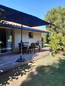 un patio con mesa y sillas bajo una sombrilla en Maison d'Amis en Salles