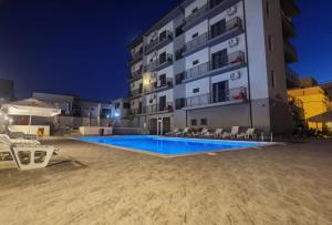 a swimming pool in front of a building at night at Kharisma Hotel in Mamaia Sat/Năvodari