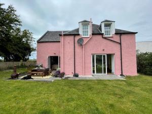 a pink house with a picnic table in the yard at Arran School House - Blackwaterfoot, Isle of Arran in Blackwaterfoot