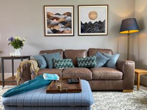 uma sala de estar com um sofá castanho e almofadas azuis em Arran School House - Blackwaterfoot, Isle of Arran em Blackwaterfoot