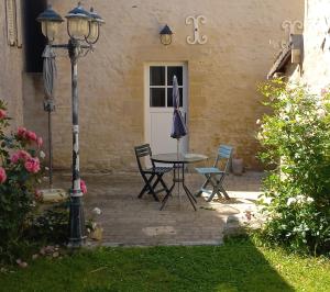 a patio with a table and chairs in front of a house at Gîte de charme Floréales Les Iris in Asnelles