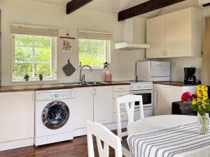 uma cozinha com uma máquina de lavar roupa e uma mesa com cadeiras em 4 person holiday home in STENHAMRA em Stenhamra