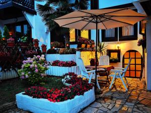 a patio with an umbrella and a table and chairs and flowers at St. Varvara Apartments in Ohrid