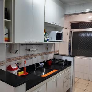 uma cozinha com armários brancos, um lavatório e um micro-ondas em Apartamento Guaruja Enseada 2 Quadra da Praia Atrás do Aquario no Guarujá