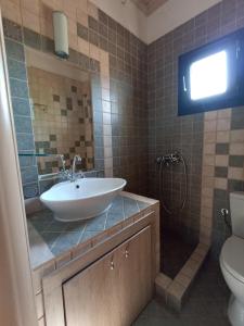 a bathroom with a sink and a toilet and a television at Olgas Villa in Aroyí