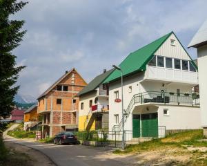 a building with a green roof on a street at Knežević Apartment in Žabljak