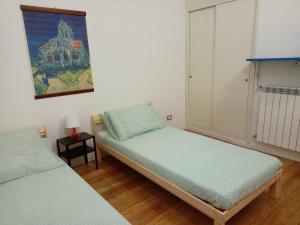 ManzianaにあるIl piccolo loftのベッド2台が備わる客室で、壁には絵画が飾られています。