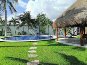 a resort with a swimming pool and a grass roof at Quinta Punta Sam in Cancún