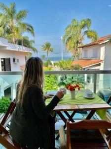 a woman sitting at a table looking out at the ocean at Pousada Tortugas in Guarujá