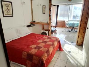 a bedroom with a bed with a red blanket and a table at DEPARTAMENTO BARILOCHE centro in San Carlos de Bariloche
