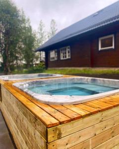 a hot tub in a wooden deck with a house at Blue Hotel Fagrilundur - On The Golden Circle in Reykholt