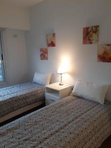 sypialnia z 2 łóżkami i stołem z lampką w obiekcie Parque Patricios 2 ambientes w BuenosAires