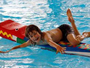 a young child laying on a raft in a swimming pool at 6 person holiday home in Sk rb k in Skærbæk