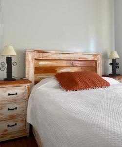 a bedroom with a bed with a wooden headboard and two lamps at Casita de Piedra 3 in Trinidad