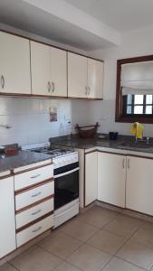 Una cocina con gabinetes blancos y un horno de estufa. en Apartamento La Felicidad, en Tandil