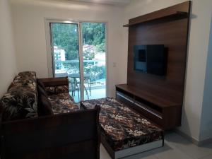 a living room with a couch and a flat screen tv at Excelente Opção de Apartamento em Ubatuba-SP in Ubatuba