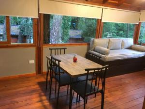 a living room with a table and chairs and a couch at Cabañas Entre Pinos in Villa Gesell