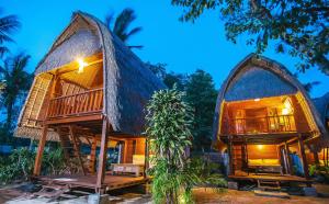 un complejo con una casa con techo de paja y porche en Sukanusa Luxury Huts, en Nusa Lembongan