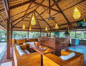 odkrytą restaurację z drewnianymi stołami i krzesłami w obiekcie Sukanusa Luxury Huts w mieście Nusa Lembongan