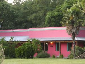 uma casa cor-de-rosa com uma palmeira à frente. em Casa de Campo La Colorada em Las Flores