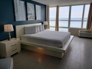 a bedroom with a large bed with blue walls and windows at Unit 1005 at Sun N Sand Resort in Myrtle Beach