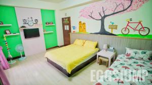 een slaapkamer met een bed en een boom en een fietsmuurschildering bij 台東愛格斯 Egg's Jump B&B Bike Tour in Taitung
