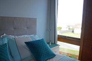 1 cama con almohadas azules junto a una ventana en Garland Grove, en Ocean Grove