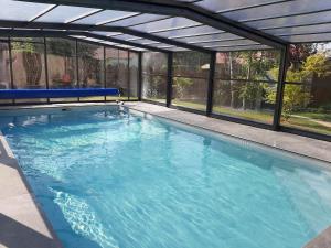 a swimming pool with a pergola and blue water at SAKURA in Fontaine-le-Comte