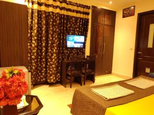 um quarto de hotel com um quarto com uma mesa e uma televisão em Pearl Premium Homes, Family BnB Guest-House em Nova Deli