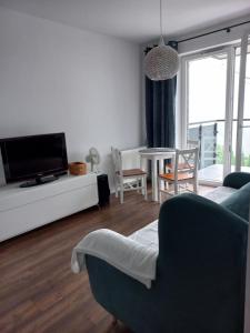 a living room with a tv and a couch and a table at Apartament - malowniczy Augustów in Augustów