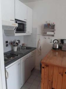 eine weiße Küche mit einer Spüle und einer Theke in der Unterkunft Les Terrasses du Mont blanc in Le Praz de Lys