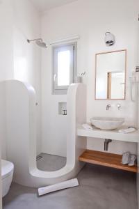 a white bathroom with a sink and a mirror at Pénde Suites in Livadion +32 photos