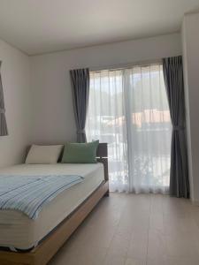 1 dormitorio con cama y ventana grande en Blue House, en Nago