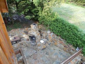 a stone fireplace in a yard with a bench at Noclegi ''U Wandy'' in Polańczyk