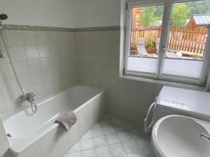 a bathroom with a tub and a sink and a window at Ferienwohnung Laimer, Radau 37 in St. Wolfgang