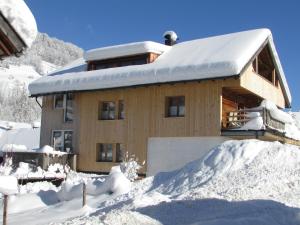a house covered in snow with a pile of snow at CHALET 294 in Mellau