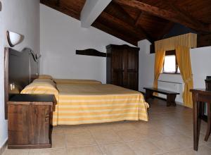 a bedroom with a bed with a yellow and brown blanket at Hotel Pietrapanna in Calvello
