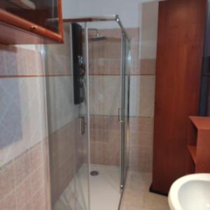 La salle de bains est pourvue d'une douche avec une porte en verre. dans l'établissement Alma, à Porto Torres