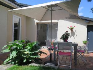 einen Tisch und Stühle unter einem Sonnenschirm auf einer Terrasse in der Unterkunft chez Annick in La Flèche