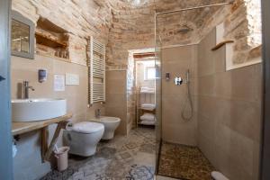 e bagno con lavandino, servizi igienici e doccia. di Trulli Holiday Deluxe & Wellness ad Alberobello