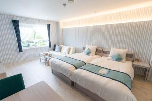 een hotelkamer met 2 bedden en een bank bij Pine Hills Hotel Miyakojima in Miyako Island