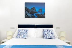 - une chambre dotée d'un lit blanc avec des oreillers bleus et blancs dans l'établissement Casetta Caprile, à Anacapri