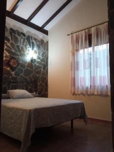 1 dormitorio con cama y pared de piedra en La solana de turon. El pino, en Ardales